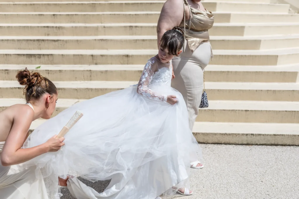 une demoiselle d'honneur replace la robe d'une petite fille